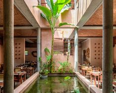 the inside of a restaurant with tables, chairs and a fish pond in the center