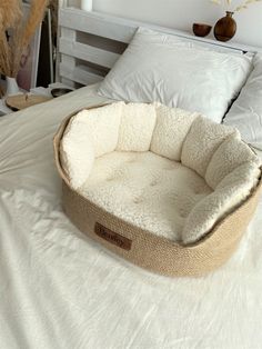 a dog bed on top of a white bed in a room with pillows and blankets