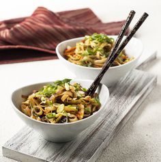 two white bowls filled with noodles and vegetables