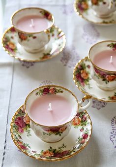 tea cups and saucers with pink candles in them