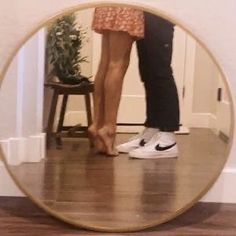 two people standing in front of a mirror with their feet on each other's legs