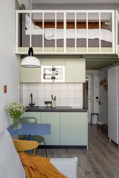 a loft bed is above the kitchen and dining area in this small apartment with white walls