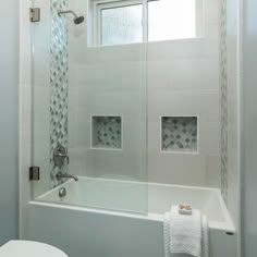 a bathroom with a glass shower door, toilet and bathtub in the middle of it