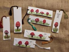 four bookmarks with red mushrooms and green grass on them are laid out next to each other