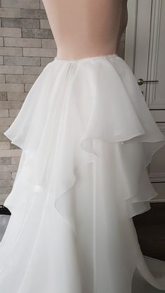 the back of a white wedding dress with ruffles on it's skirt