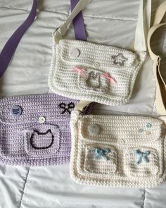 three crocheted purses sitting on top of a white bed next to each other