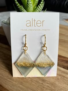 a pair of earrings sitting on top of a table next to a potted plant