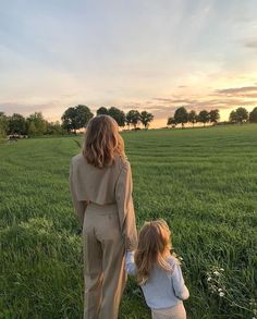 a woman and child walking through a field