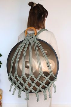 a woman holding a large metal pan with tassels