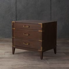 a wooden dresser with three drawers on it's sides, against a gray wall