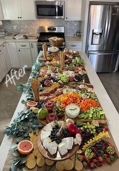 a long table filled with lots of food on top of a kitchen counter next to a refrigerator