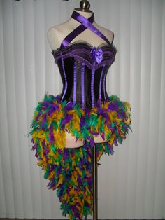 a mannequin with purple and yellow feathers on it's torso, standing in front of a white wall