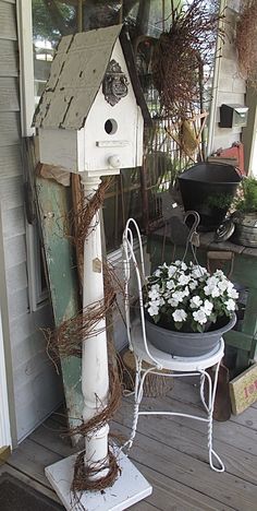 a bird house sitting on top of a white table next to a potted plant