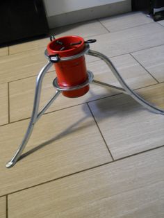 a red bucket sitting on top of a metal stand