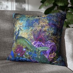 a decorative pillow on a couch in front of a potted plant with purple and green flowers