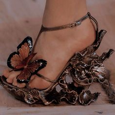 a woman's foot with butterfly decorations on the toe and ankle strap, as seen from above