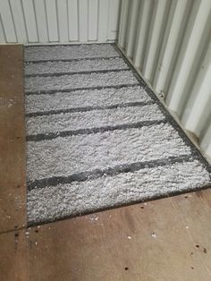 a white area rug sitting on top of a wooden floor next to a metal container