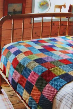 a bed with a colorful quilt on it in a room next to a wooden wall