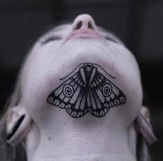 a black and white photo of a woman's head with a moth tattoo on it