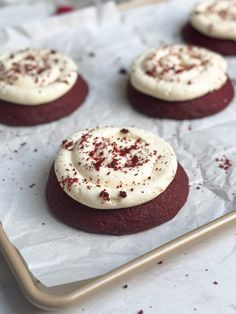 red velvet cookies with white frosting and sprinkles on a baking sheet