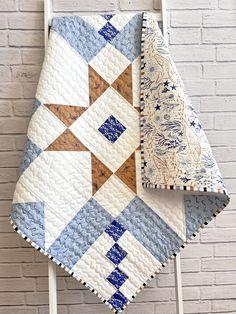 two blue and white quilts hanging on a brick wall