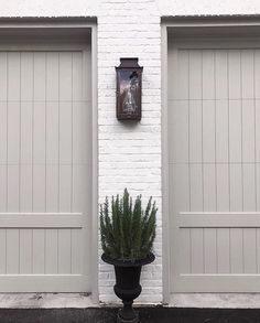 a white brick building with two doors and a potted plant