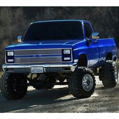 a blue pickup truck parked on top of a dirt road