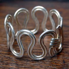 a silver cuff bracelet sitting on top of a wooden table