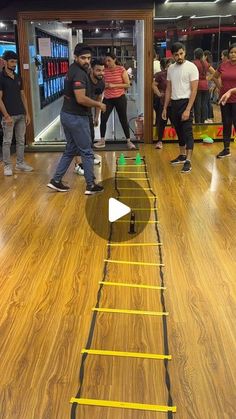 a group of people standing on top of a hard wood floor next to a ladder