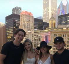 four people posing for a photo in front of the city skyline