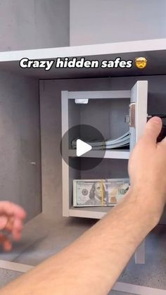 a man is opening a safe with money in the other hand and pointing at it