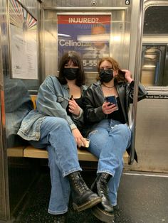 two women sitting on a subway bench wearing face masks