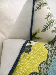 a close up of a pillow on top of a white couch with green and blue designs