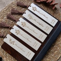 five wooden name tags with tassels on top of a table next to flowers