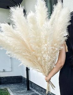 a woman in a black dress holding a bunch of white flowers with her hands behind her back