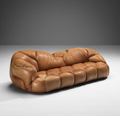 a brown leather couch sitting on top of a white floor next to a gray wall