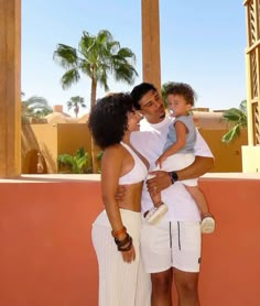 a man, woman and child are posing for a photo in front of palm trees