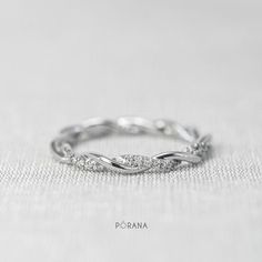 a white gold wedding band with diamonds on top and the words porana written below it