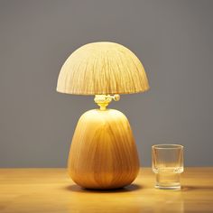 a wooden table with a glass next to it and a lamp on top of it