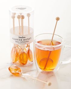 a glass cup filled with liquid and spoons on top of a white countertop