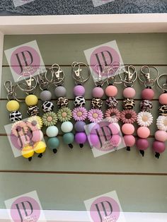 a bunch of key chains are hanging on a wall with the letters d and p