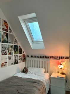 a bedroom with a bed and a skylight in the corner, along with pictures on the wall