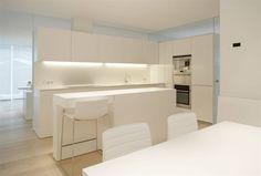 the kitchen is clean and ready to be used for cooking or dining, with all white furniture