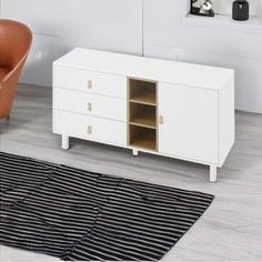 a white cabinet sitting on top of a hard wood floor next to a brown chair