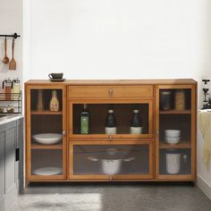 a wooden cabinet with glass doors in a kitchen next to a sink and counter top