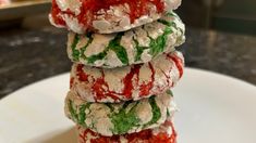 a stack of cookies covered in icing on top of a white plate with red and green sprinkles