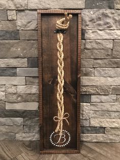 a wooden sign with a rope hanging from it's side on a stone wall