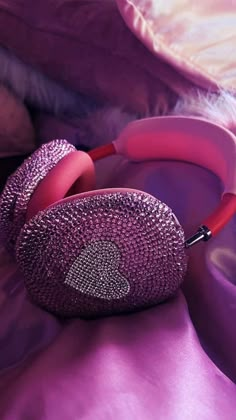 a pair of headphones laying on top of a purple bed cover with pink pillows