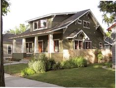 a house with green siding and white trim on the front door, grass in front yard