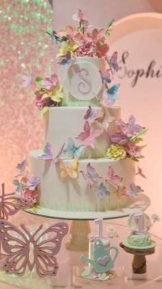 there is a three tiered cake with butterflies on the top and one number on the bottom